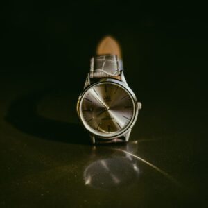 Classic silver wristwatch with leather strap showcased on a reflective surface, perfect for a touch of elegance.